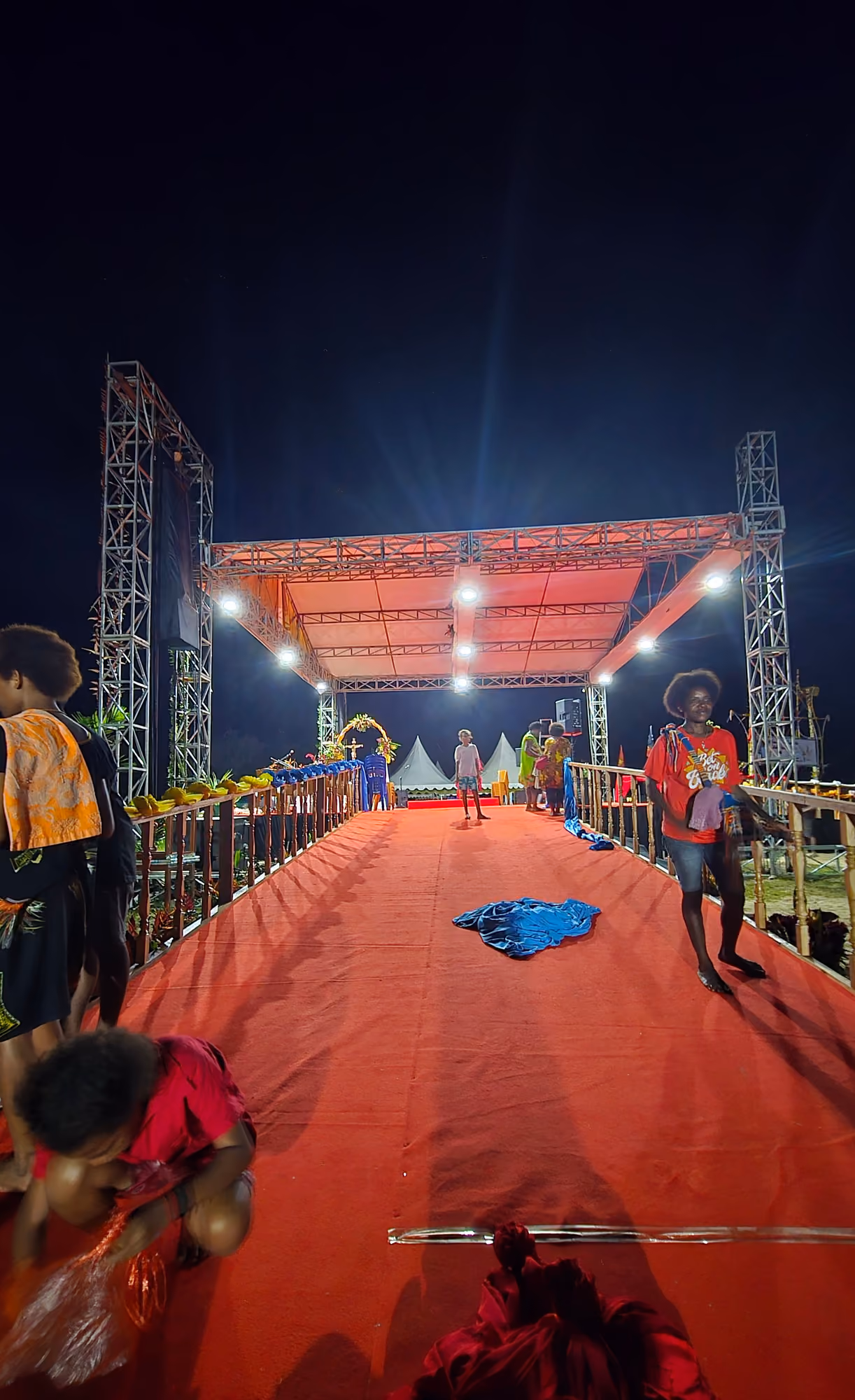 Jalur panggung berkarpet merah dengan rangka lampu menjulang di kedua sisi pada malam hari.