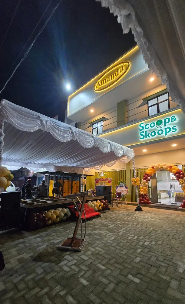 Area peresmian gerai pada malam hari dengan tenda dekorasi, balon, dan lampu.