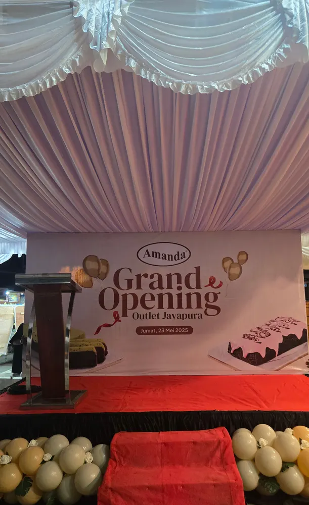 Backdrop peresmian gerai dengan panggung rendah dan karpet merah di depannya.