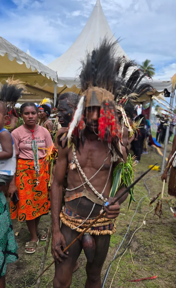 Penampil mengenakan busana dan hiasan kepala adat Papua di area acara.