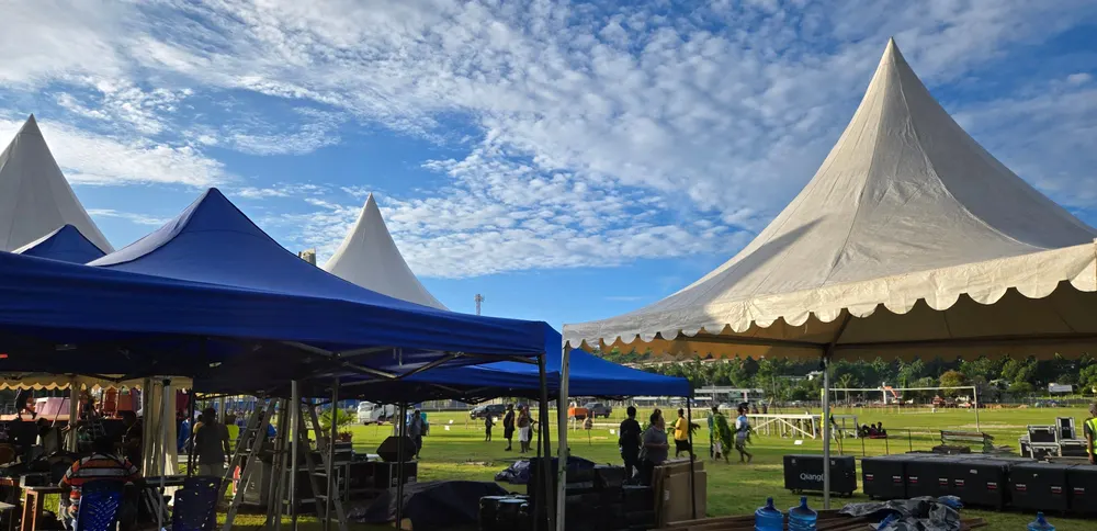 Deretan tenda putih berdiri di lapangan terbuka dengan langit cerah berawan.