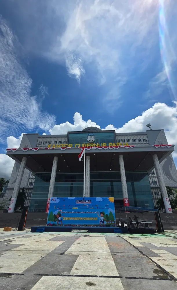 Gedung berpilar tinggi dengan area acara yang telah tertata di halamannya.