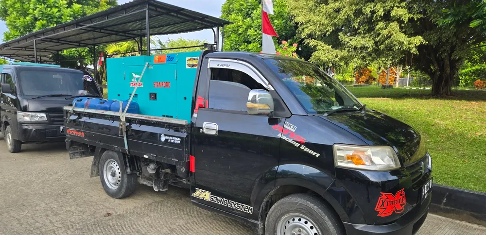 Genset diangkut menggunakan kendaraan bak terbuka menuju lokasi acara.