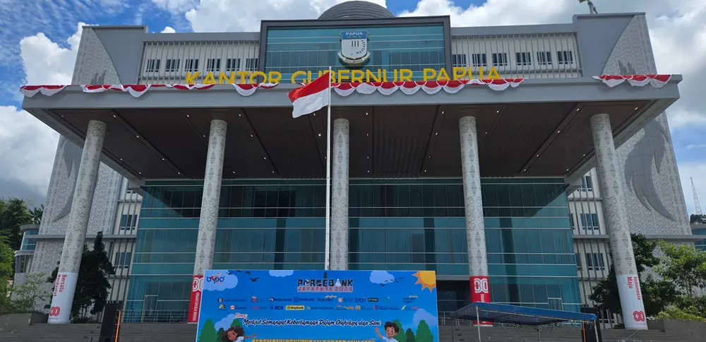 Halaman gedung berpilar ditata dengan backdrop acara dan dekorasi merah putih.