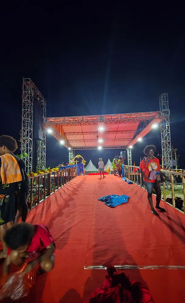 Jalur panggung berkarpet merah dengan rangka lampu menjulang di kedua sisi pada malam hari.
