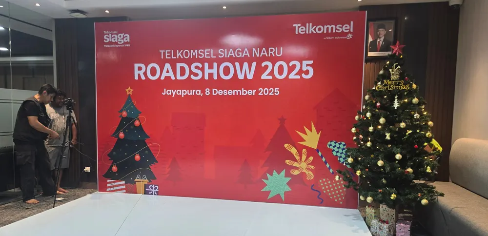 Panggung rendah dan backdrop merah siap dipakai di ruang acara dalam gedung.