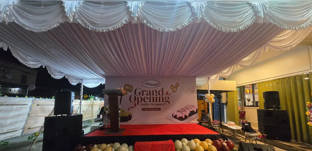 Panggung peresmian dengan backdrop, karpet merah, dan dekorasi balon di sekelilingnya.