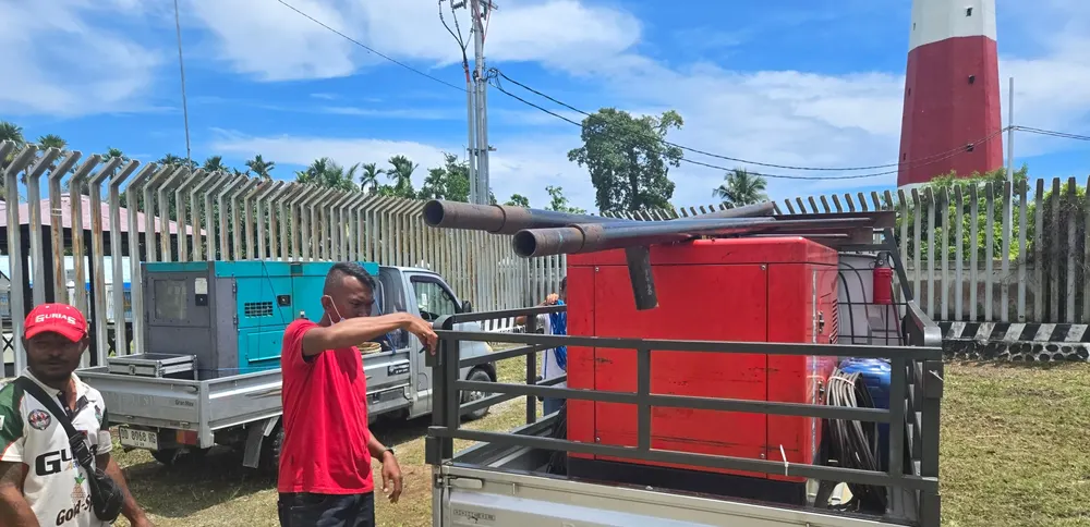 Peti peralatan berwarna merah diangkut menggunakan kendaraan bak terbuka.
