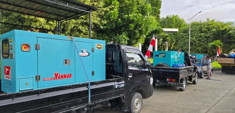 Unit genset berdiri di atas kendaraan bak terbuka, siap dimobilisasi.
